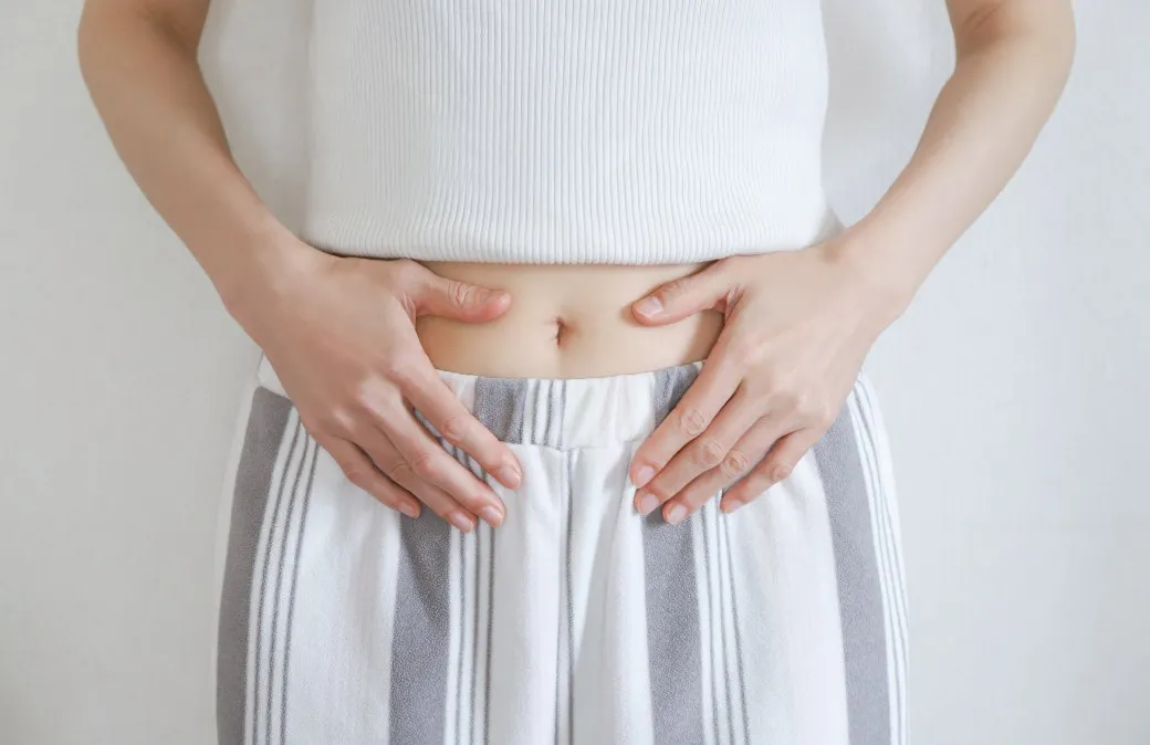 お腹に手を当てる女性のイメージ