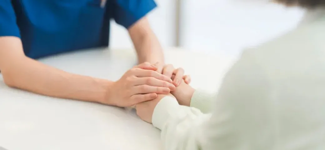 患者の手を取り説明する医療スタッフ