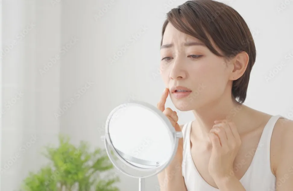 鏡で顔のできものを気にする女性